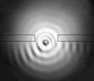 This photo shows the droplet bouncing through one slit while its trajectory is deflected by the interference of the reflected waves from two slits.